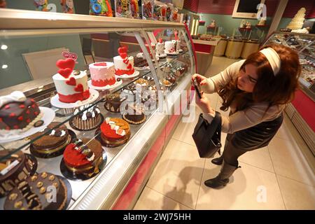 Beyrouth, Liban. 13 février 2024. Une femme prend des photos de gâteaux pour la Saint-Valentin dans un magasin de desserts à Beyrouth, Liban, le 13 février 2024. Crédit : Bilal Jawich/Xinhua/Alamy Live News Banque D'Images