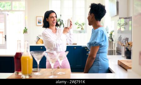 Deux amies féminines matures à la maison s'amuser à mélanger des cocktails ensemble Banque D'Images