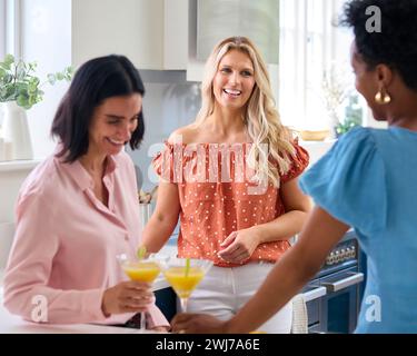Trois amies féminines matures à la maison s'amuser à boire des cocktails dans la cuisine ensemble Banque D'Images
