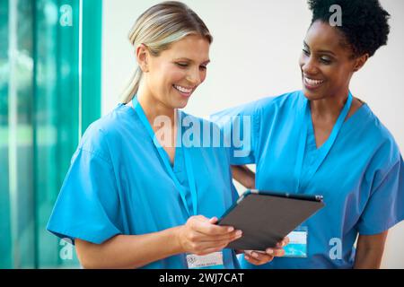 Deux docteurs matures portant des gommages avec tablette numérique discutant des notes du patient à l'hôpital Banque D'Images