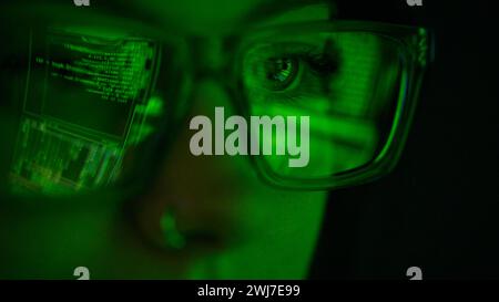 Gros plan de l'écran réfléchi dans Glasses of Female Computer Hacker Writing Code Banque D'Images