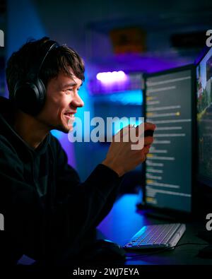 Prise de vue à faible éclairage de touche d'un joueur masculin devant des écrans d'ordinateur avec casque et contrôleur Banque D'Images