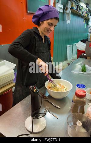 Cuisinière préparant la garniture pour les pâtes dans son étal de l'ancien marché central d'Abaceria à Barcelone Banque D'Images