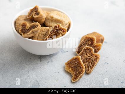 Figues blanches organiques sucrées séchées dans un bol en céramique sur fond clair. Banque D'Images