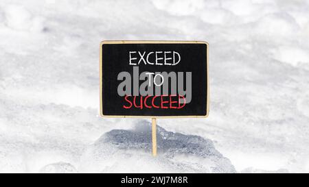 Symbole dépasser pour réussir. Les mots conceptuels dépassent pour réussir sur un beau tableau noir de craie noire. Beau fond de neige blanc. Et dépasse jusqu'à Banque D'Images