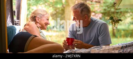 Couple senior Camping dans la campagne relaxant boire du café à l'intérieur du RV Banque D'Images