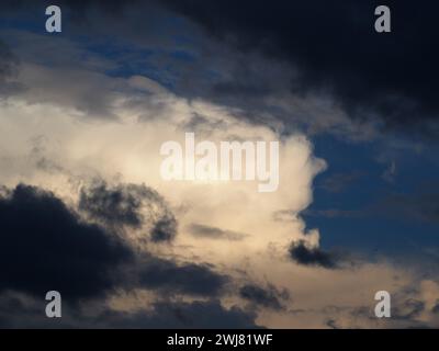 Silhouette d'avion volant à travers les nuages du coucher du soleil Banque D'Images