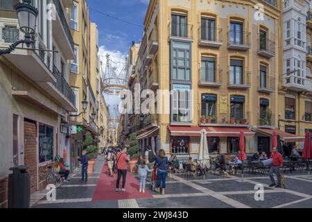 Les gens marchant sur un tapis rouge sur le sol de la rue Trapper pleine de boutiques et de décorations de Noël dans la capitale de la région de Murcie, en Espagne. Banque D'Images