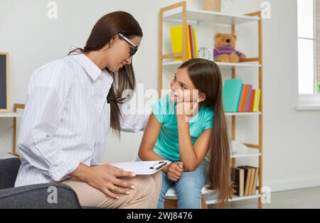 Adolescente regarde avec confiance la femme psychologue assise à côté d'elle dans la classe d'école. Banque D'Images