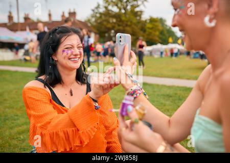 Deux amies féminines regardant Glitter Make Up au Festival de musique d'été Banque D'Images