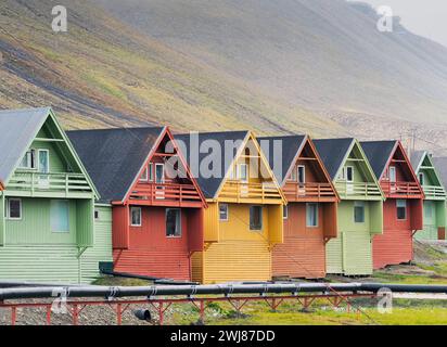 Longyearbyen, Norvège. 22 août 2023. Les bâtiments résidentiels peints en vert, rouge, brun et jaune sont construits à flanc de montagne. Fondée en 1906 comme colonie minière sur l'île principale, la ville a un aéroport à proximité et est généralement le point de départ pour des excursions au Spitzberg. Crédit : Soeren Stache/dpa/Alamy Live News Banque D'Images