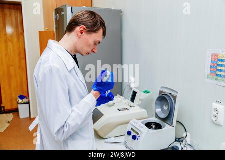 Scientifique avec la main gantée plaçant l'échantillon d'ADN dans PCR-cycler en temps réel. Banque D'Images