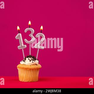 Bougie numéro 132 - anniversaire cupcake sur fond rouge rhodamine Banque D'Images