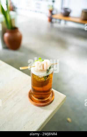 Boisson fraîche de thé de litchi sur une table avec un café élégant en arrière-plan. Banque D'Images