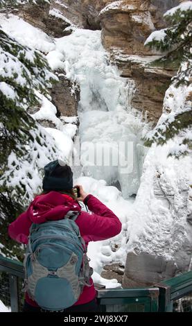 Le touriste prend des photos de Johnston Canyon Waterfall - Frozen Lower Falls avec piscine turquoise sous le parc national Banff AlbertaCanada Banque D'Images