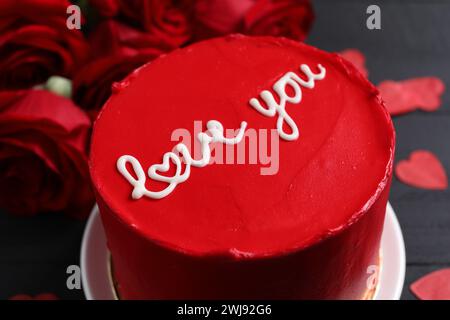 Bento gâteau avec texte Love You et roses sur la table noire, gros plan. Prog Surprise pour la Saint-Valentin Banque D'Images