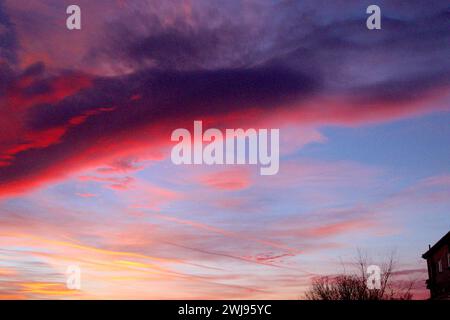 Spectaculaire coucher de soleil surréaliste avec traînées de vapeur d'avion dans le ciel captant les rayons de lumière du soir, contraste avec les nuages multicolores. Banque D'Images