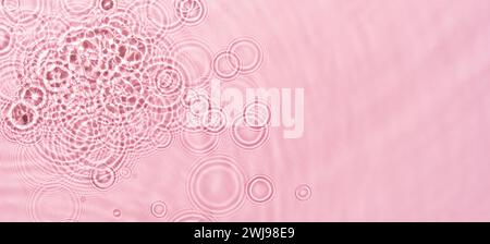 Ondulations de l'eau sur fond rose. Texture abstraite des ondulations de l'eau. Banque D'Images