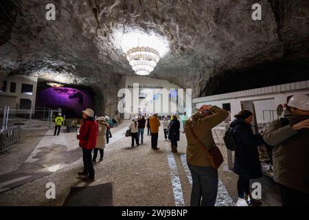 Plusieurs visiteurs traversent l'entrée principale de la mine Bergtatt. Bergtatt est une mine de marbre exceptionnelle située dans le comté de Møre og Romsdal, près de la ville d'Eide, dans la région occidentale de la Norvège. Il propose des visites guidées à travers des grottes souterraines. L'expérience comprend une promenade en bateau sur un lac de métro illuminé et une salle de concert sculptée dans le marbre. Le site est connu pour sa beauté naturelle et son acoustique unique, ce qui en fait une destination mémorable pour les visiteurs. Banque D'Images