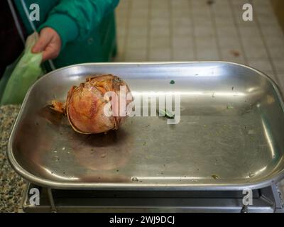 le vendeur de femme senior pèse gros oignon rose organique dans une balance à l'image haute résolution de magasin de détail Banque D'Images