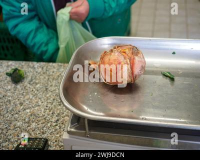 le vendeur de femme senior pèse gros oignon rose organique dans une balance à l'image haute résolution de magasin de détail Banque D'Images