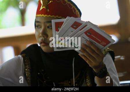 Sleman, Yogyakarta, Indonésie. 14 février 2024. Un officier du Groupe d'organisation du vote habillé en danseurs bédouins (l'un des éléments du patrimoine culturel immatériel de l'Indonésie de la région spéciale de la province de Yogyakarta) organise les bulletins de vote lors des élections présidentielles et législatives indonésiennes dans l'un des bureaux de vote de Sleman. Le vote a commencé le 14 février lors des élections présidentielles, nationales et provinciales en Indonésie dans plus de 800 000 bureaux de vote à travers le pays, avec près de 205 millions de personnes éligibles pour voter. (Crédit image : © Angga Budhiyanto/ZUMA Press Banque D'Images