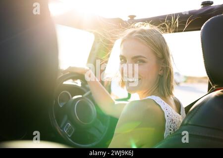 Jeune femme caucasienne sourit en conduisant sur un Road trip Banque D'Images