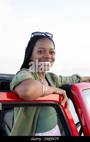 Jeune femme afro-américaine s'appuie sur une porte de voiture lors d'un voyage en voiture Banque D'Images