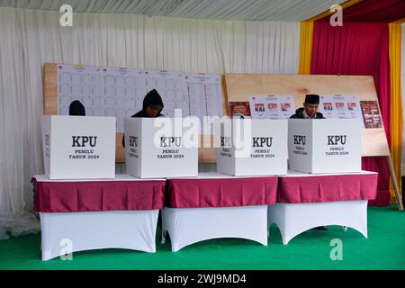 Bogor, Indonésie. 14 février 2024. Les électeurs remplissent les bulletins de vote au bureau de vote no 35 à Bogor, Indonésie, le 14 février 2024. Le vote pour les élections générales en Indonésie a officiellement commencé mercredi matin, selon la Commission électorale générale (KPU) du pays. Crédit : Xu Qin/Xinhua/Alamy Live News Banque D'Images