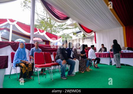 Bogor, Indonésie. 14 février 2024. Les électeurs attendent de recevoir leur bulletin de vote au bureau de vote no 35 à Bogor, Indonésie, le 14 février 2024. Le vote pour les élections générales en Indonésie a officiellement commencé mercredi matin, selon la Commission électorale générale (KPU) du pays. Crédit : Xu Qin/Xinhua/Alamy Live News Banque D'Images