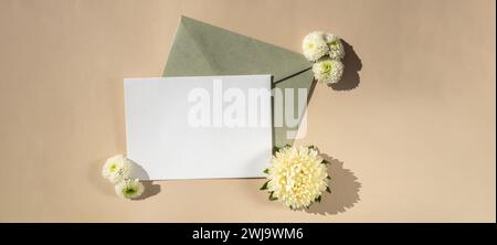 Belles petites fleurs blanches sur enveloppe verte postale sur fond beige, espace de copie de note de papier vide pour le texte, printemps, carte de voeux pour les vacances. Concept de livraison de fleurs Banque D'Images