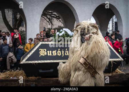 Busó marchant à côté du cercueil - l'un des symboles du Mohács Busójárás 2024 - pendant la procession de Buso, avec la foule debout sur le côté Banque D'Images