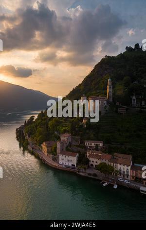 Coucher de soleil pittoresque sur les eaux tranquilles d'un village historique de Morcote, région de Lugano. Banque D'Images