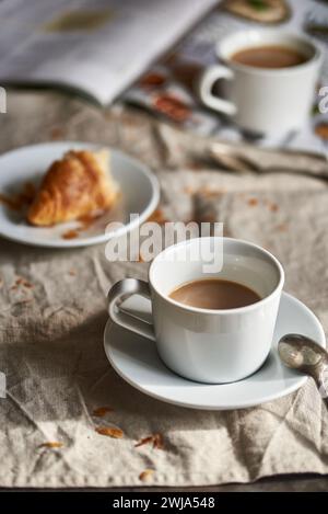 Pause café confortable avec un croissant frais sur une table rustique. Banque D'Images