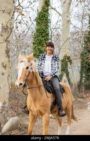 Jeune femme cavalière chevauchant sa jument brune dans la nature Banque D'Images
