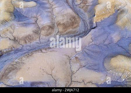 Vue aérienne de motifs désertiques abstraits avec un lit de rivière sec serpentant à travers un terrain sablonneux texturé dans l'Utah, États-Unis Banque D'Images