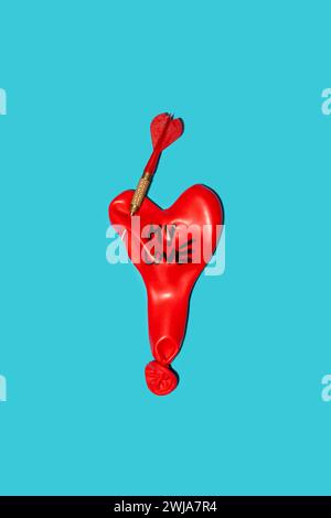 Ballon dégonflé en forme de coeur rouge avec cou noué et perçage de fléchettes sur le dessus avec inscription My Love placé sur fond bleu dans la lumière Banque D'Images
