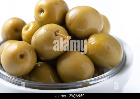 Olives vertes dans un bol blanc isolé sur fond blanc. Banque D'Images