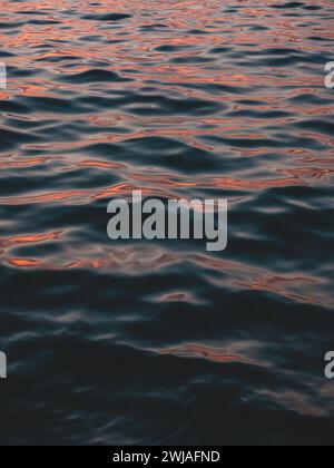 L'eau avec des vagues douces et des reflets de coucher de soleil. Banque D'Images