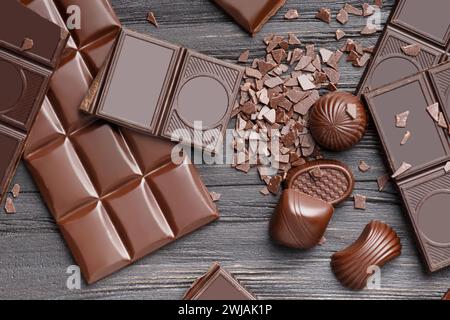 Composition créative de barres de chocolat brisées et entières, de chocolats et de pépites de chocolat sur une vue de dessus de fond en bois foncé. Banque D'Images