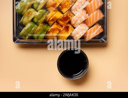 Un ensemble de rouleaux de sushi multicolores lumineux avec crevettes, saumon, avocat dans un emballage en plastique sur un fond clair, vue de dessus. Livraison de sushis Banque D'Images