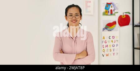 En-tête avec un jeune enseignant vietnamien souriant debout en classe Banque D'Images
