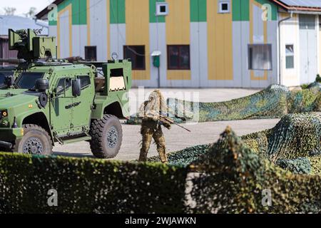 Un soldat en vêtements de camouflage et un véhicule militaire blindé vert lors d'un spectacle Banque D'Images