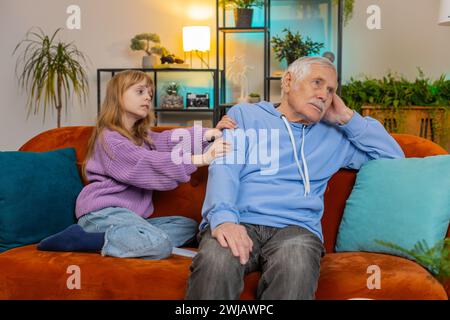Compassion. Aimer petite-fille gentille inquiète consolant grand-père triste aidant avec le problème réconfortant parler à un homme âgé bouleversé, empathie, soutien embrassant assis sur le canapé dans le salon. Banque D'Images