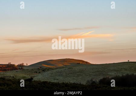 Deux personnes regardant le coucher du soleil lors d'une promenade nocturne d'hiver dans la campagne frontalière galloise à Llandegley, près de Llandrindod Wells, Powys, Royaume-Uni Banque D'Images