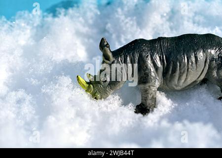 Rhinocéros jouet pour enfants photographié en gros plan. Un rhinocéros se dresse sur la neige blanche. Photo de haute qualité Banque D'Images