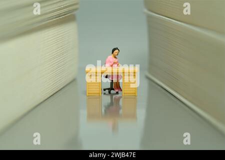 Miniature Tiny People jouet figure photographie. Une femme siège bibliothécaire sur le bureau dans l'allée de la bibliothèque. Photo d'image Banque D'Images