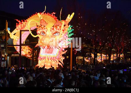 Pékin, Chine. 14 février 2024. Les gens regardent une lanterne géante en forme de dragon à une foire dans le district de Xicheng à Pékin, capitale de la Chine, le 14 février 2024. Les gens à travers la Chine apprécient la fête du printemps en cours de différentes manières. Crédit : Ju Huanzong/Xinhua/Alamy Live News Banque D'Images