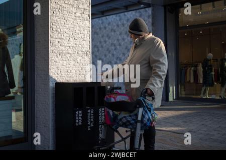 Novara, Italie, 16 janvier 2024 : un homme âgé utilisant un déambulateur à roues prend une pause-tabac dans le centre commercial Banque D'Images