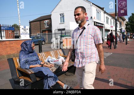 Asian Man passe devant Asian Woman à Bury Park, une partie multiculturelle de Luton dans le sud-est du Royaume-Uni Banque D'Images